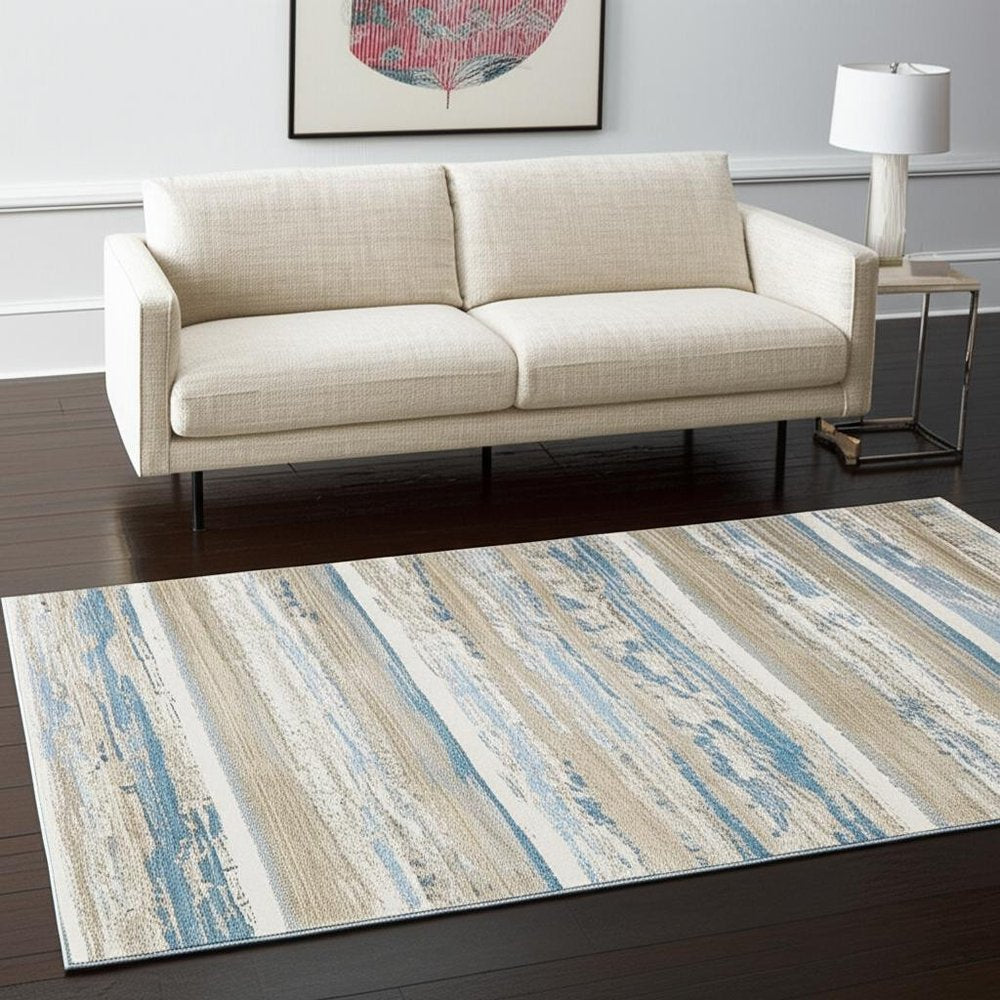 5' X 8' Ivory Beige Grey Blue And Tan Abstract Power Loom Stain Resistant Area Rug With Fringe